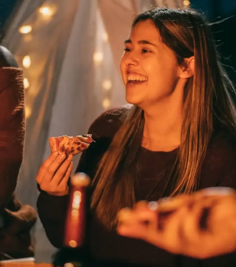 Mujer feliz disfrutando de comer en una reunión de amigos